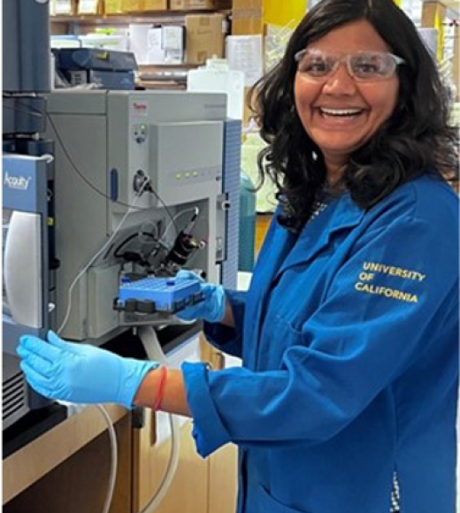 Latika Singh smiling while standing a lab bench