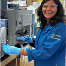 Latika Singh smiling while standing a lab bench